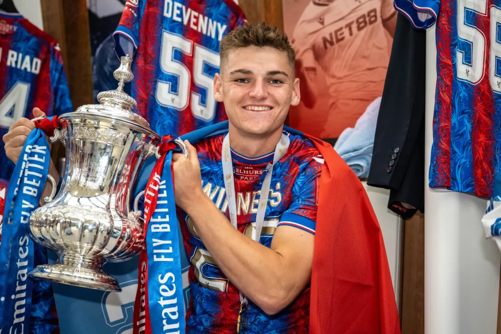 Justin Devenny holding the FA Cup trophy in Crystal Palace kit, celebrating victory at Selhurst Park stadium